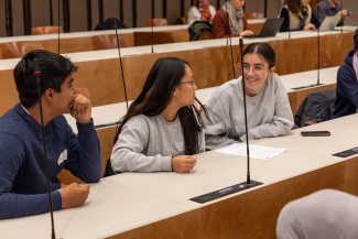 Jugendliche diskutieren im Rathaus Zürich ihre Anliegen an die Stadt und lachen zusammen vor den Mikrofonen.